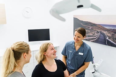 Zahnärztin und Mitarbeiterin D. Vogelbein in Gespräch mit Patientin.