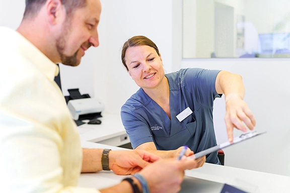 Mitarbeiterin D. Vogelbein in gespräch mit Patienten.