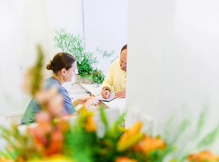 Praxismanagerin D. Vogelbein bespricht Anamnesebogen mit Patient.