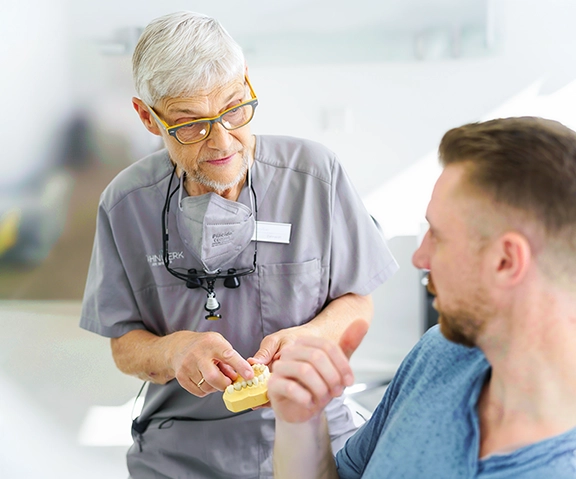 Dr. Ralf Voßler in Gespräch mit Patient zum Thema Zahnersatz.